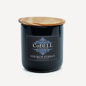 Black candle jar with wooden lid and Cobell Candles label on a white background